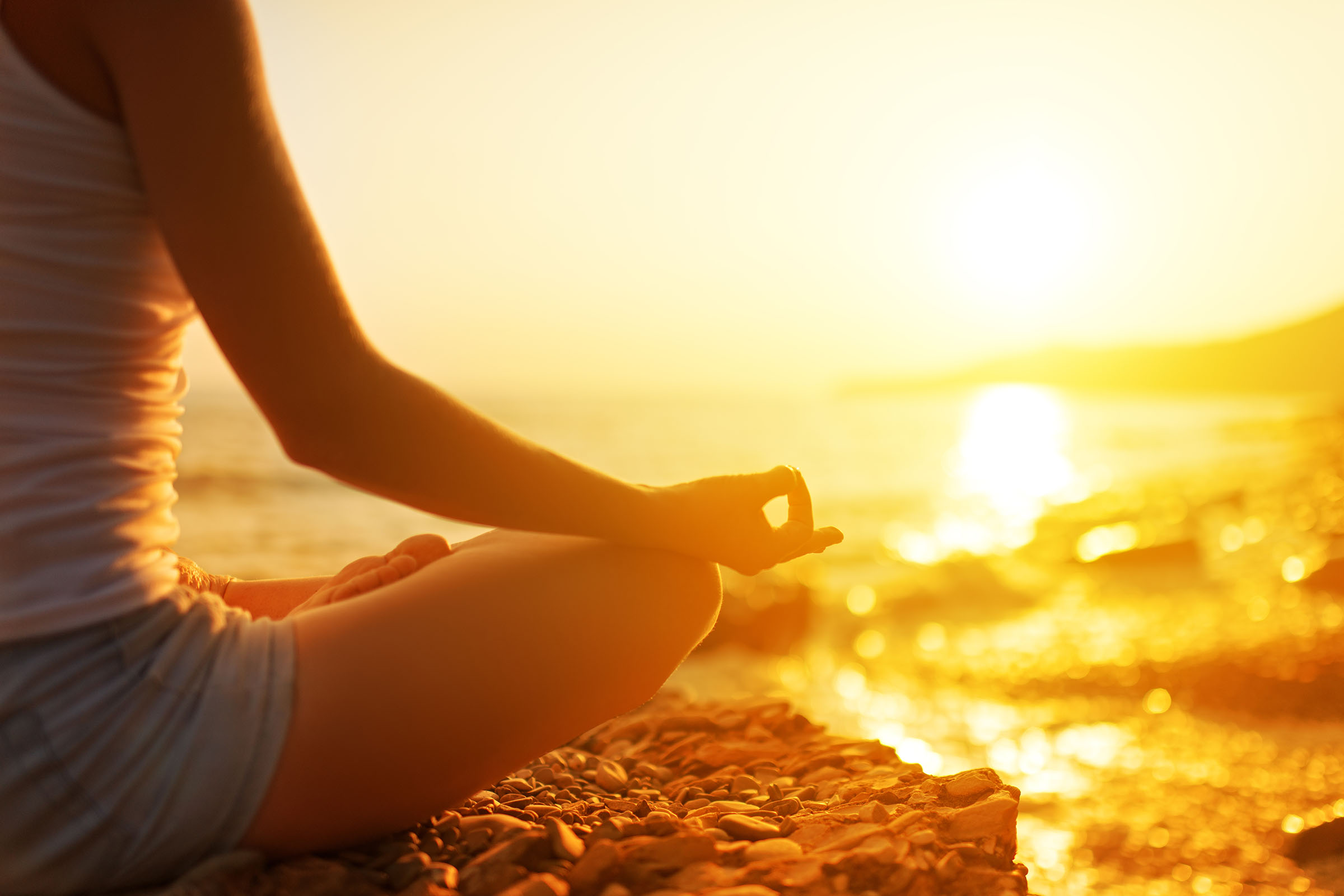 hand of a woman meditating in a yoga pose on the beach
